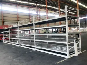A multi-tiered vertical farming system with rolling racks filled with vibrant green seedlings. Each level features white ebb and flow trays, illustrating an efficient hydroponic setup for modern agriculture. The racks are closely packed to maximize space, with one aisle opened to show the rolling mechanism.
